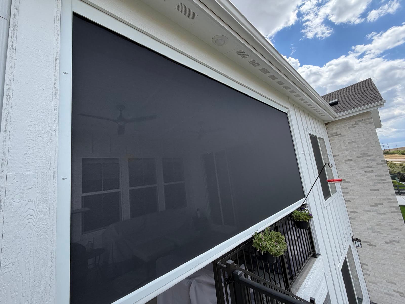 An exterior screen seen from the yard, shading a covered deck