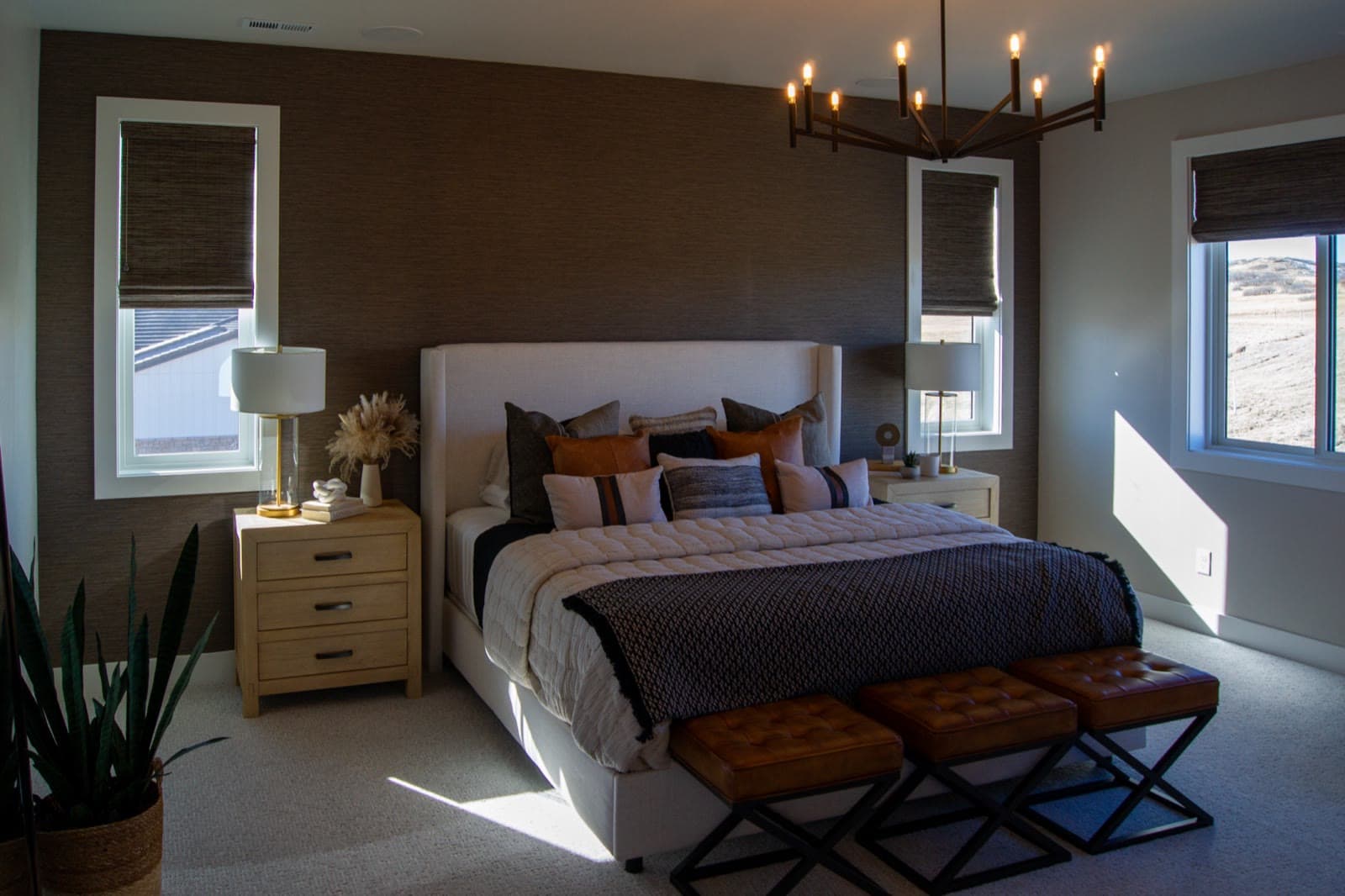 Grasscloth walls and deep-toned Romans flanking the bed in the primary suite