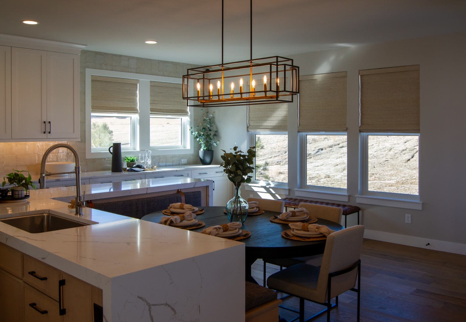 Woven wood Roman shades over a kitchen sink and dining nook with open-space views