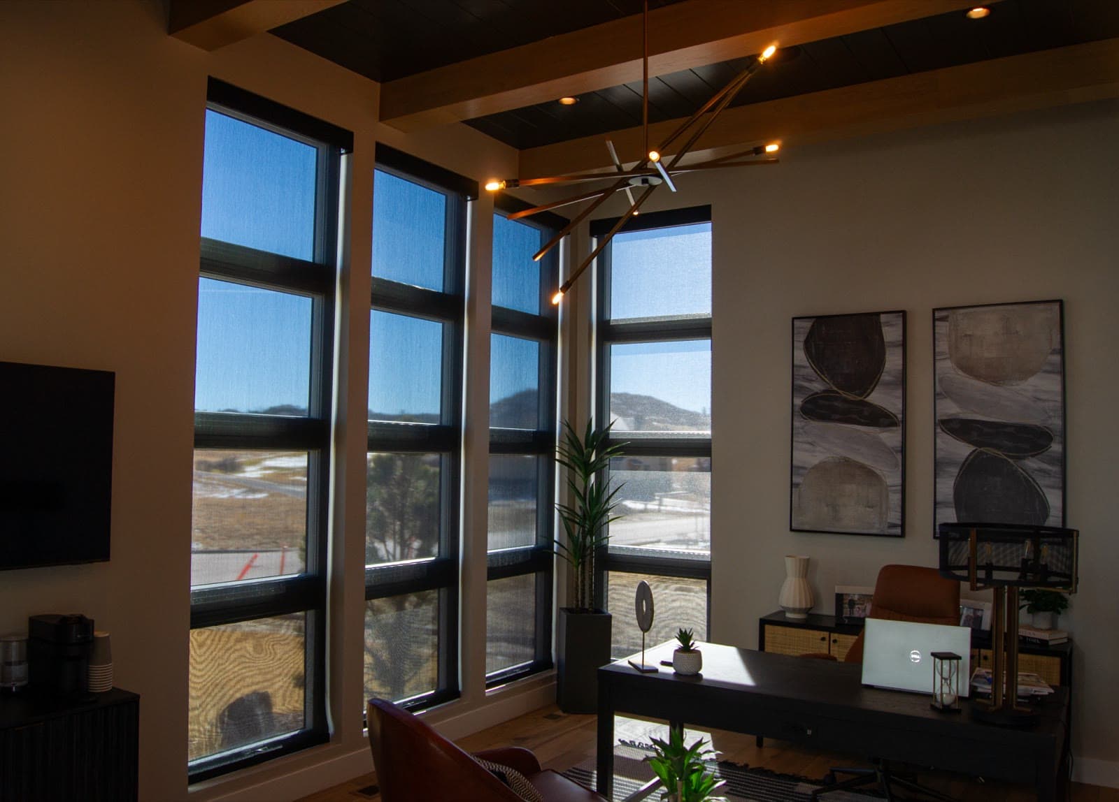 Floor-to-ceiling solar roller shades in a home office with foothill views