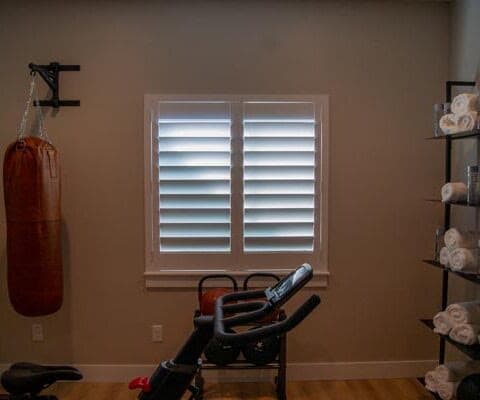 Plantation shutters in a home gym with the louvers tilted closed