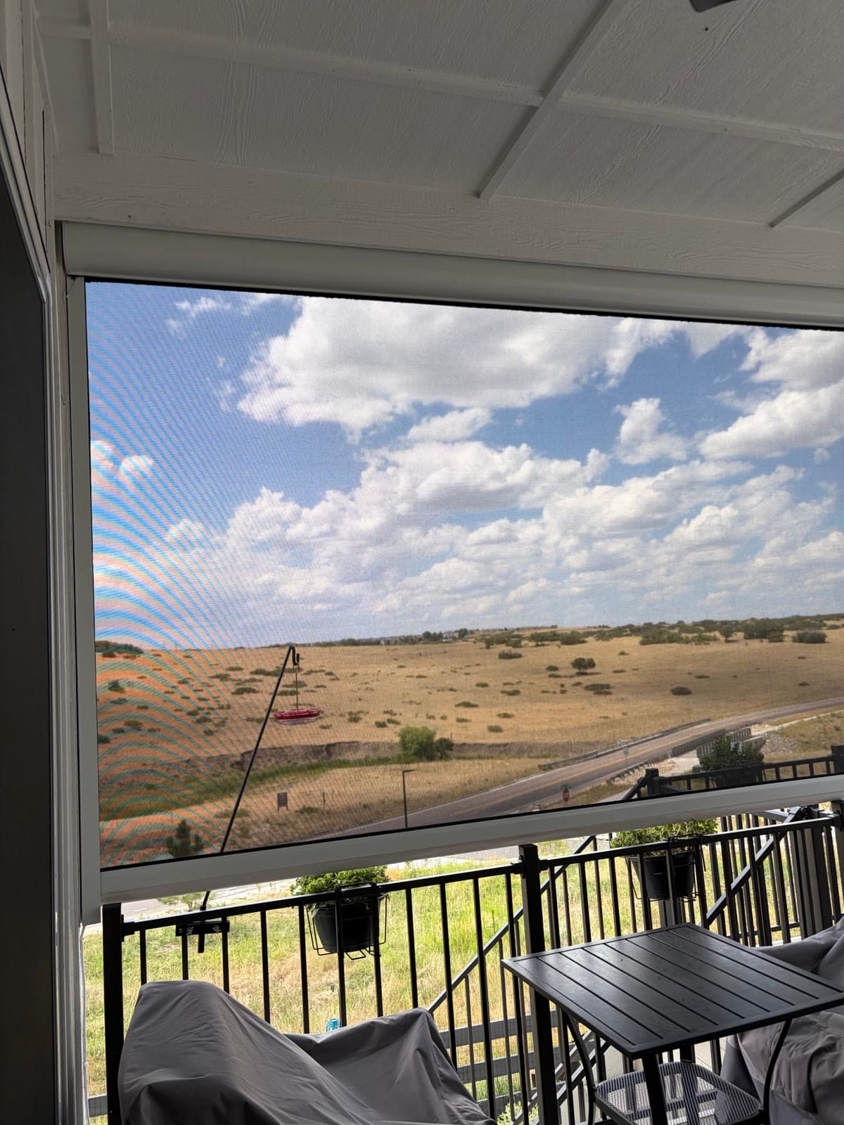 Prairie and clouds seen straight through the lowered patio mesh