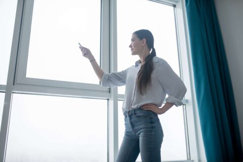 A woman pointing to a window in a room